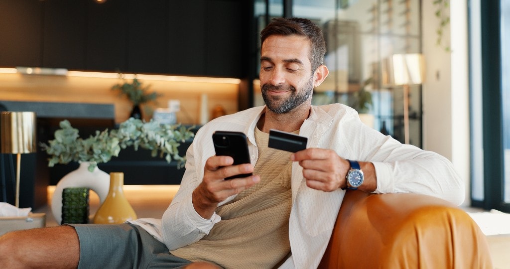Customer paying by link on a phone while holding a card at home